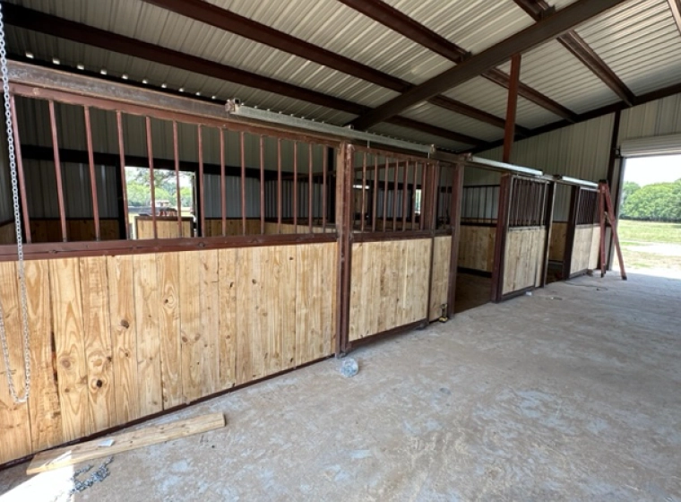 metal barn building with some brown metal structure a concrete floor and brown fences