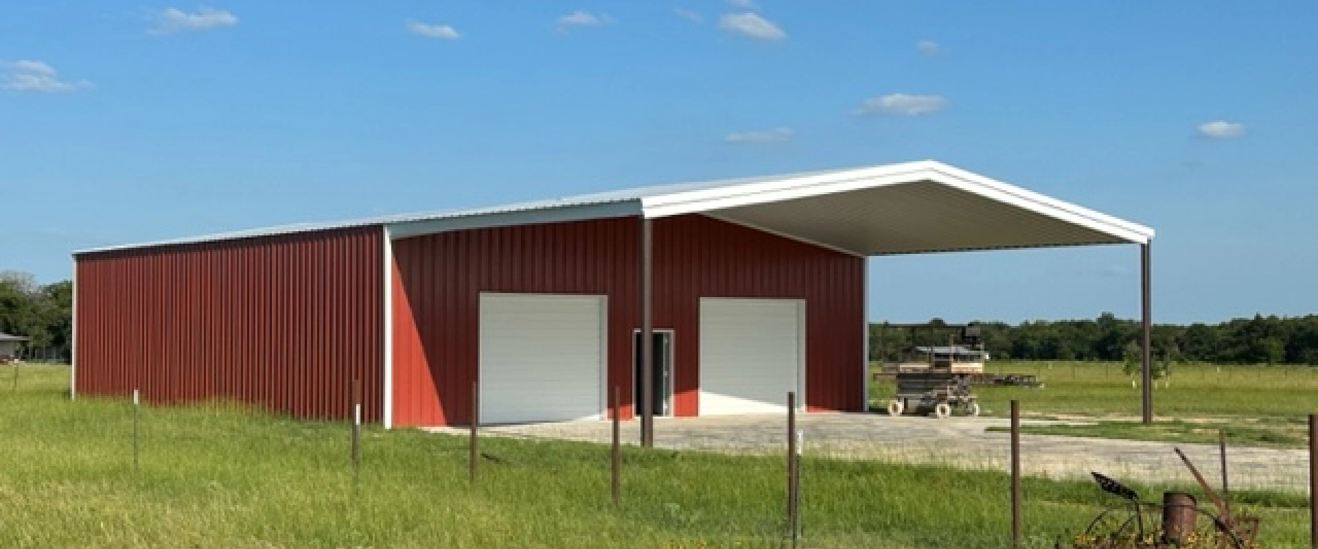 red farm with white doors and a metal ceiling with some grass around